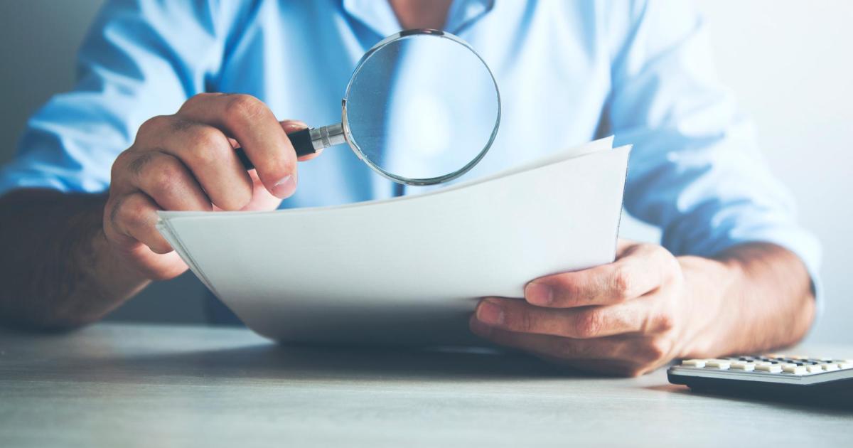 Man use magnifying glass on document