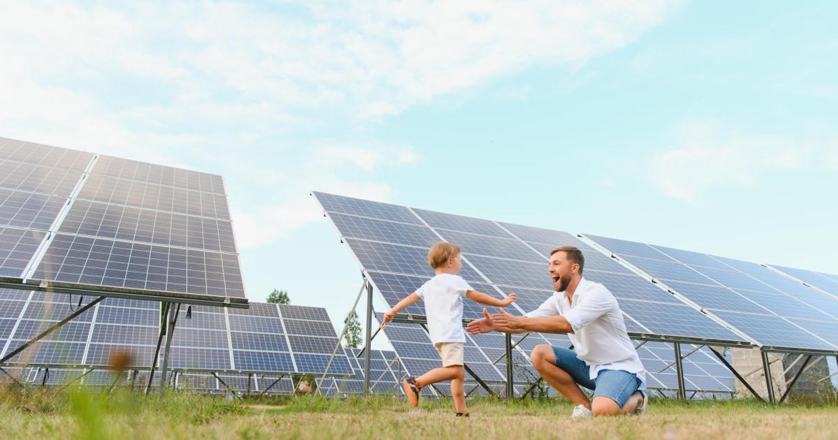 Father and son running in front of solar panel